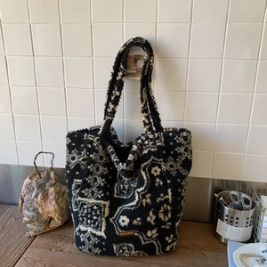 Detail of plush tote bag with paisley pattern and brown leather brand label