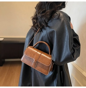 Brown vintage PU leather shoulder bag with textured surface and top handle shown on model
