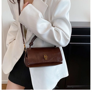 Detail of vintage dark brown faux leather crossbody bag with golden twist lock and knot strap