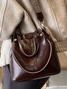 Dunkelbraune Leder-Beuteltasche mit gewebtem Riemen und metallischen Nietendetails
