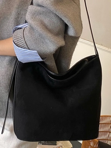 Minimalist black matte leather tote bag for women worn over shoulder with large capacity
