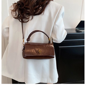 Close-up of a brown leather shoulder bag with a gold metal clasp and soft vintage texture