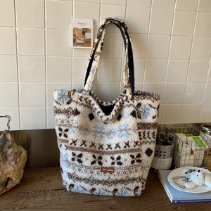Detail of soft fleece tote bag with blue snowflake patterns and leather brand patch