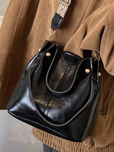 Glänzende schwarze Beuteltasche mit breitem Jacquard-Gurt und goldenen Details