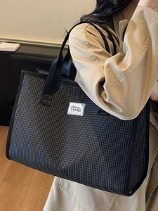 Large capacity black and white checkered tote bag with woven straps on a model
