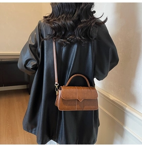 Back view of model wearing a vintage brown crossbody bag with a black leather jacket
