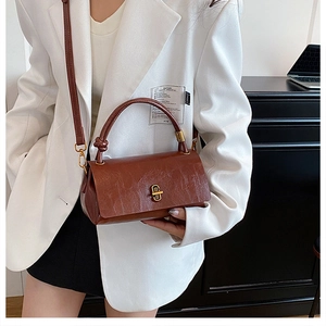 Detail of vintage brown leather handbag with knotted handle and metallic twist lock