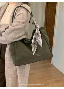 Detail of dark green suede tote bag with decorative black and white patterned silk scarf