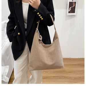 Detail of beige textured leather tote bag with elegant shoulder strap and embossed logo