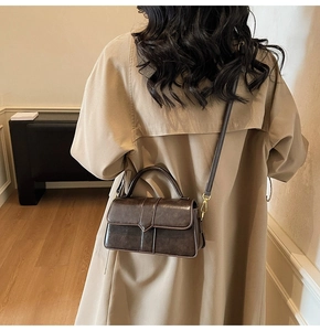 Detail view of vintage dark brown faux leather handbag with golden hardware and strap