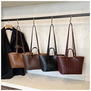 Detailed row of leather tote bags in brown, black, and burgundy on metal hooks