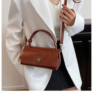 Close-up of caramel leather handbag featuring a gold twist lock and knotted handle