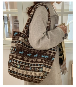 Detail of plush tote bag showing reindeer jacquard pattern and leather brand label