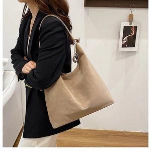 Side view of a khaki leather tote bag worn by a model in a minimalist lifestyle setting