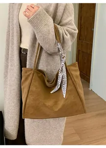Detail of camel suede tote bag with decorative silk scarf and minimalist retro vibe