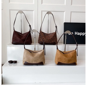 Detail view of leopard print and solid faux suede tote bags with reinforced leather base