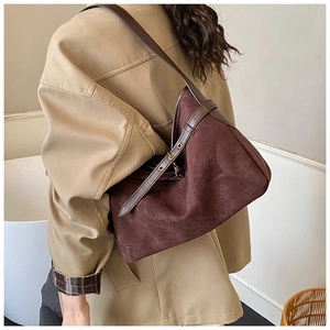 Close-up of brown suede shoulder tote bag with vintage leather strap and gold buckle