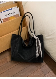 Close-up of large black tote bag with paisley silk scarf detail in a home setting