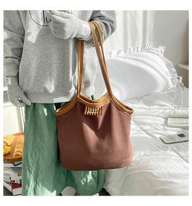 Détail d'un grand cabas en daim marron avec écusson 'Bonjour' et bordures de couleur orange
