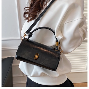 Close-up of black glossy leather handbag featuring elegant gold metal clasp and top handle