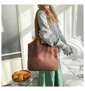Détail du sac cabas en daim marron foncé avec étiquette vintage et anse en cuir