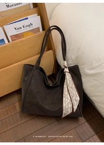 Macro view of dark brown textured tote bag featuring a paisley silk ribbon accent