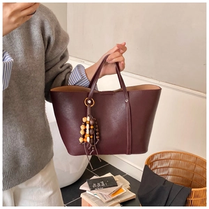 Detail of burgundy large tote bag with bohemian beaded tassel and matte PU leather texture