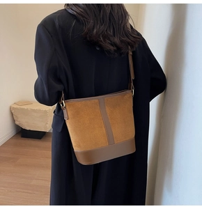 Detail of vintage suede bucket bag with leather patchwork and adjustable strap on a model
