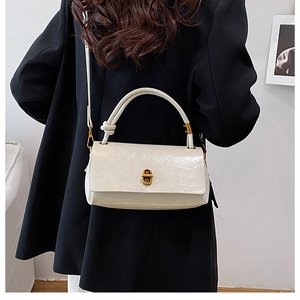 Detail of cream glossy leather handbag with golden twist lock and knotted handle