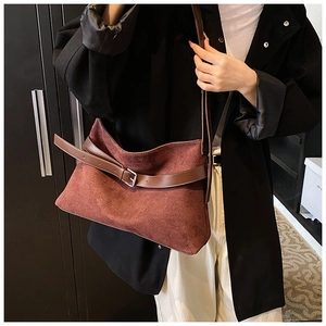 Close-up of brown suede shoulder bag with leather strap and silver buckle detail