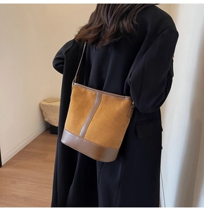 Brown suede bucket bag for women shown as a stylish shoulder bag in a minimalist setting