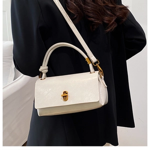 Detail of white glossy handbag featuring golden twist lock and stylish knotted strap design