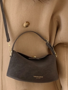 Sac bandoulière chic en cuir marron foncé avec détails dorés sur manteau beige