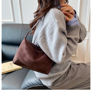 Detailed view of deep brown suede half-moon shoulder bag with smooth leather corners