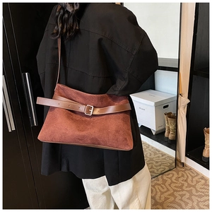 Detail of red-brown suede shoulder bag showing brown leather strap and metal buckle detail