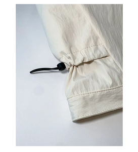Detail showing the adjustable drawstring and plastic toggle on an ivory tote bag fabric