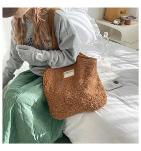 Gros plan du sac cabas marron en peluche avec étiquette SEEYOU dans un décor de chambre douillet