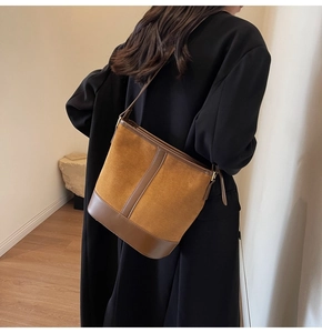 Close-up of vintage brown suede bucket bag with leather trim on model's shoulder