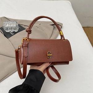 Detail of vintage brown leather bag with a gold twist lock and stylish knotted handle