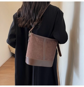 Detailed view of brown matte suede bucket bag texture on a model wearing a black wool coat