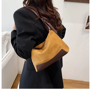 Close-up of mustard yellow suede shoulder bag with brown leather trim details