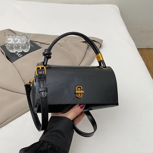 Detail of black leather handbag with gold metal buckle and adjustable shoulder strap
