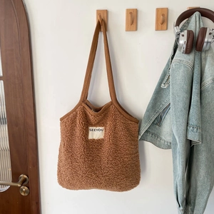 Détail du sac fourre-tout marron en peluche avec étiquette SEEYOU sur crochet mural