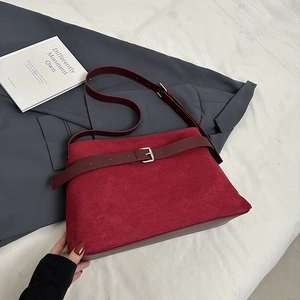 Macro detail of dark red frosted suede tote with stitching and metallic belt buckle decoration