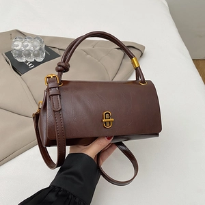 Detail of soft brown leather handbag with knot handle and vintage gold C-shaped lock