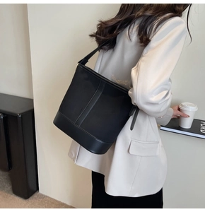 Detailed texture of black frosted bucket bag with leather trim and shoulder strap
