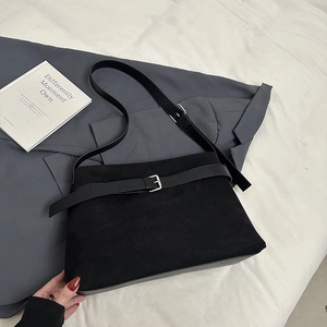 Macro detail of black frosted suede tote bag with leather strap and square metal buckle