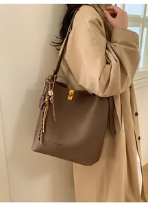Détail du cabas en cuir marron foncé avec fermoir doré et pendentif décoratif élégant