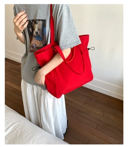 Detail of red large capacity tote bag featuring side drawstrings for daily travel use