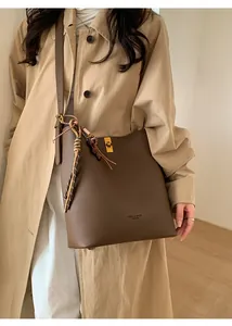 Détail d'un sac seau en cuir grainé marron foncé avec fermoir doré et gland décoratif